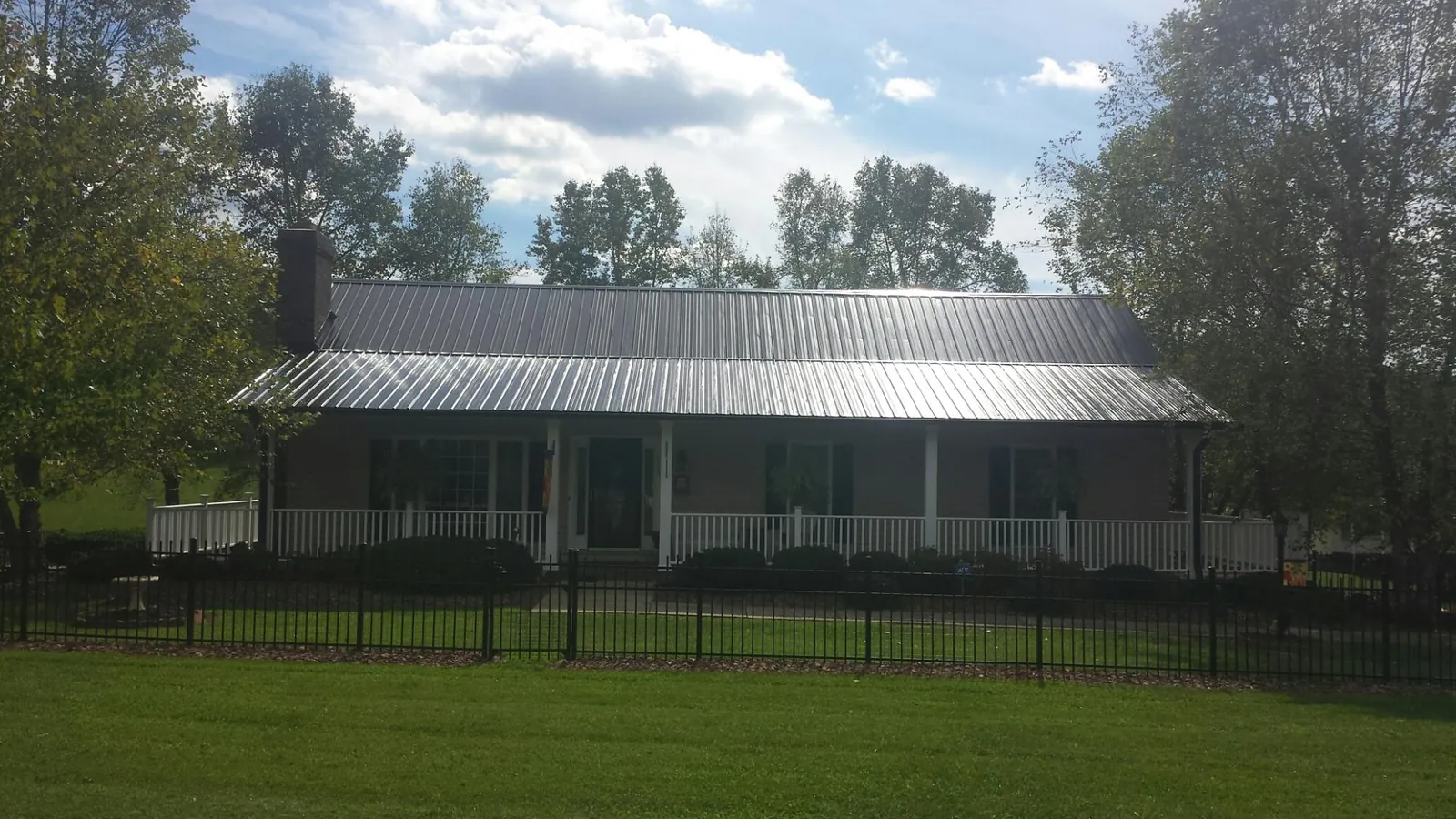 Gray metal roof on a brick ranch with a full width front porch — Gutter Guard Installation work by our crew in Plano