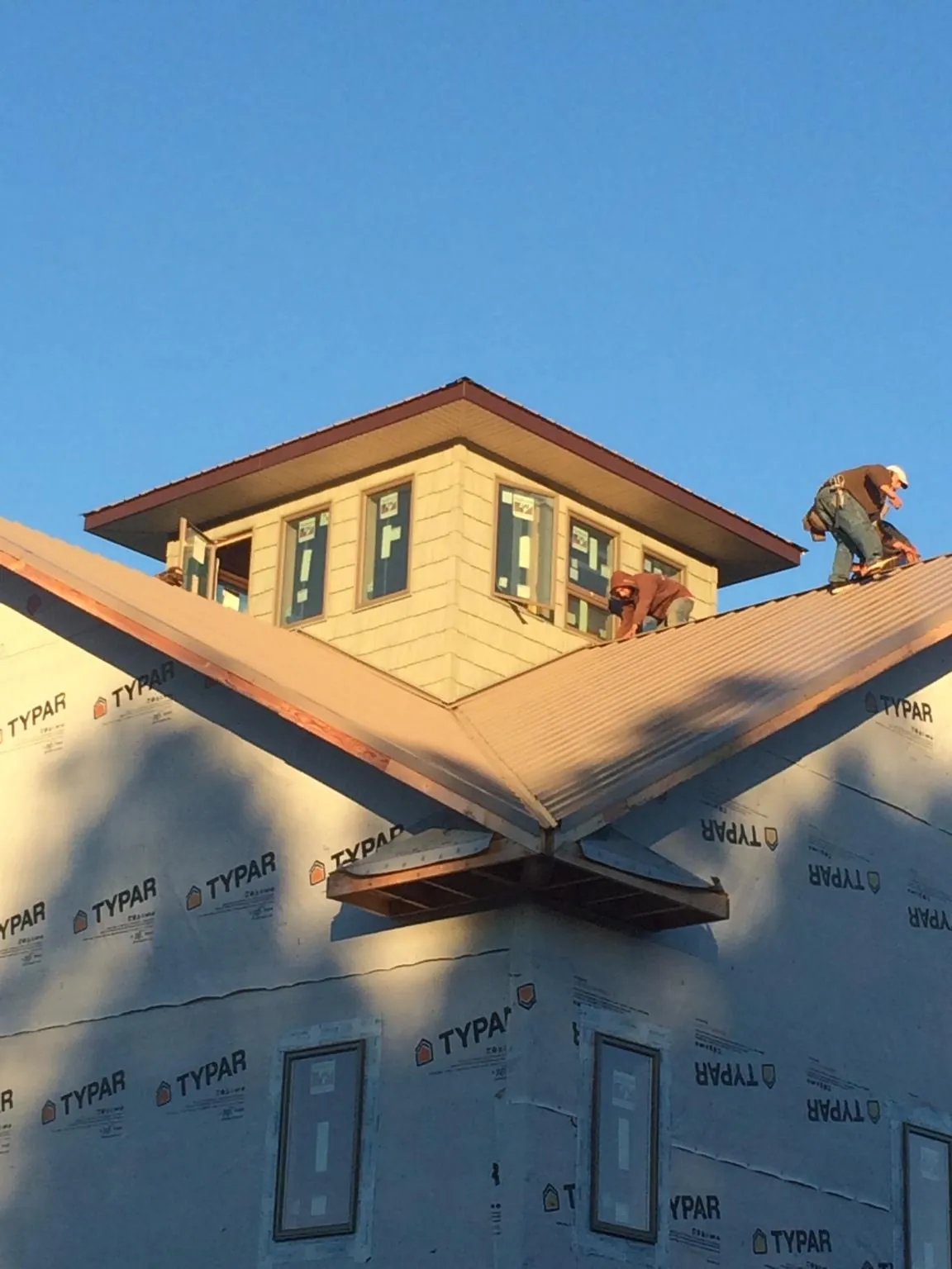 Roofers working around a rooftop cupola on a new metal roof at sunset — Roof Waterproofing in Plano by Roofing Brothers